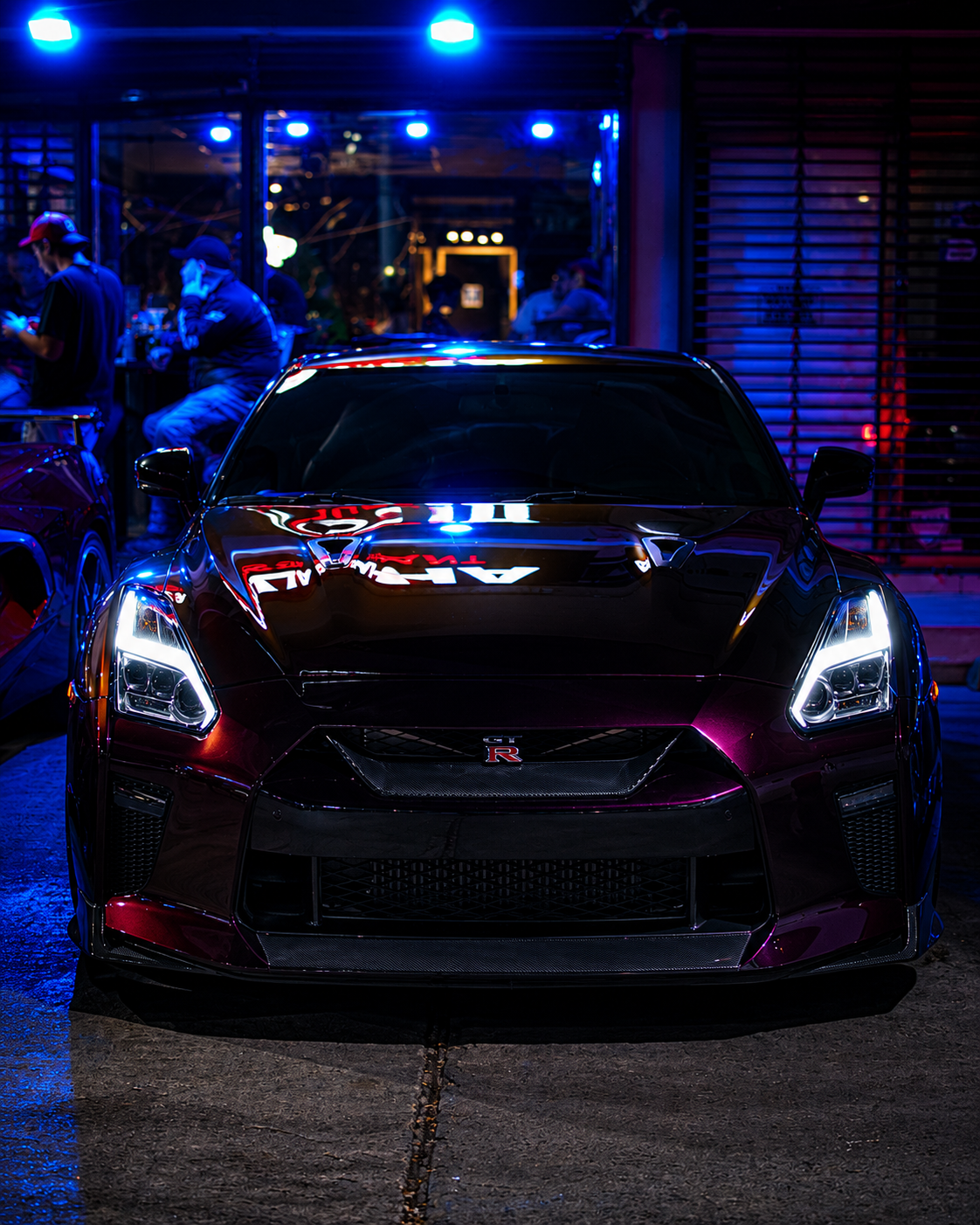 Nissan GT-R borgoña de frente con faros encendidos
