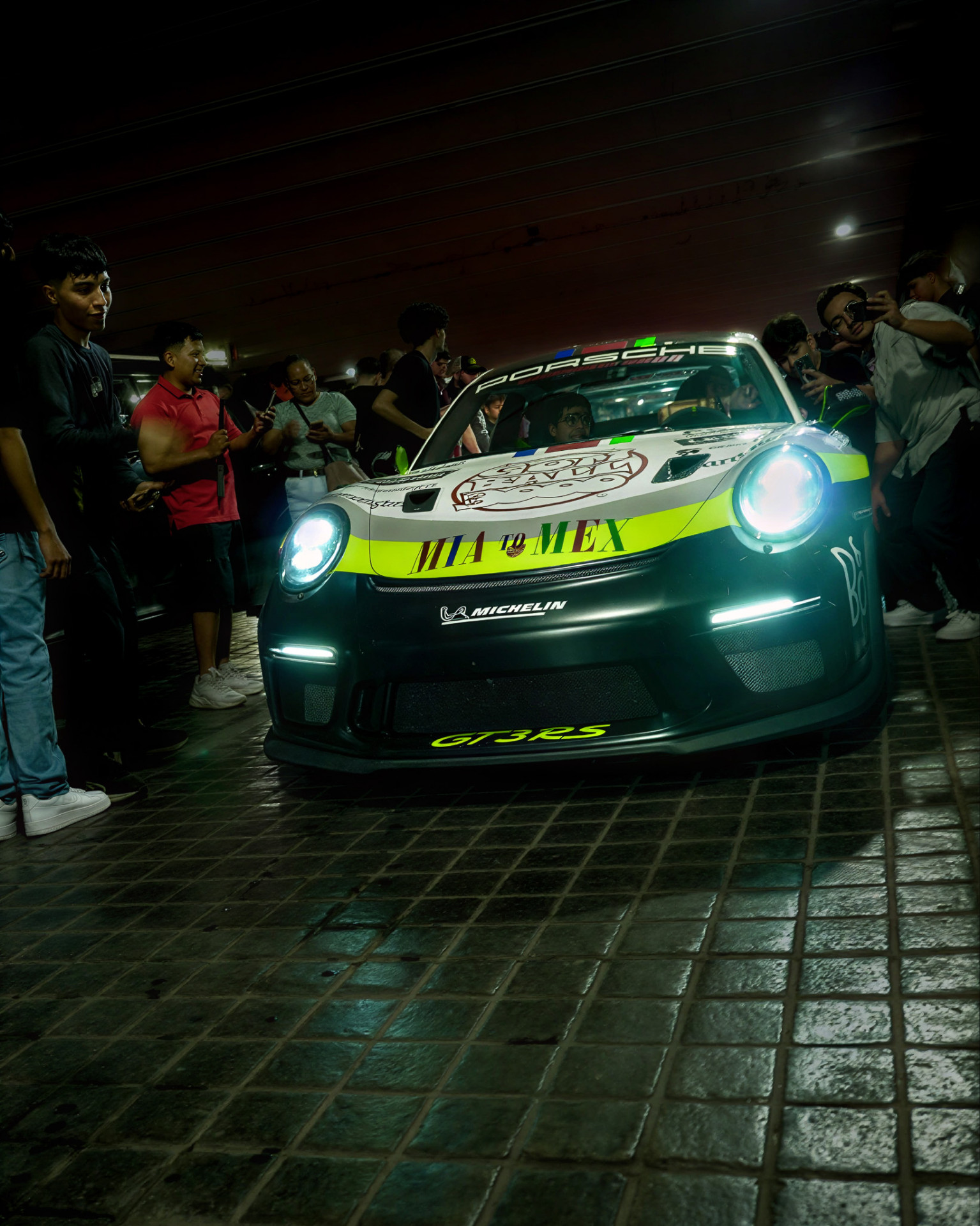 Porsche 911 GT3 RS con faros encendidos rodeado de gente